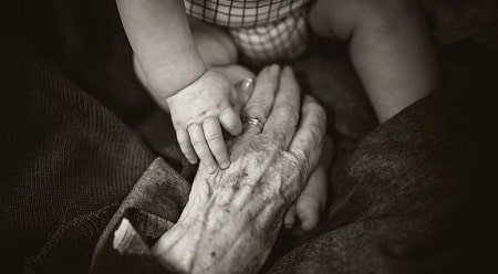 Mãos de criança e idosa